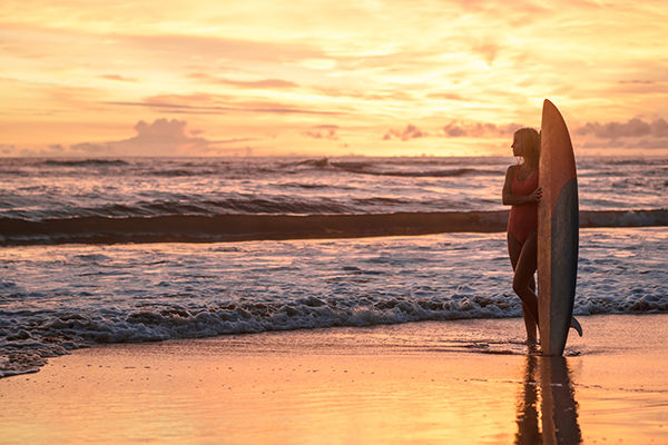 Young woman with surfboard on the beach