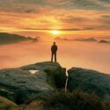 Man looking out over mountains at sunset