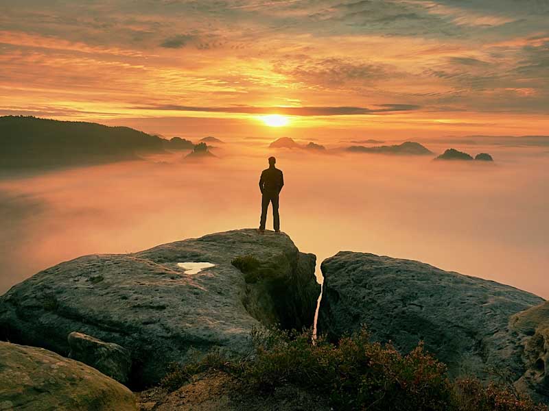 Man looking out over mountains at sunset