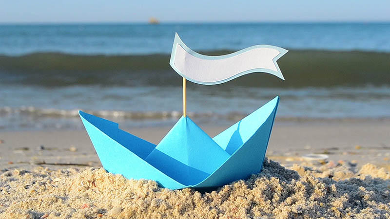 Blue paper boat on a beach