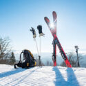 Skiis, gloves, and a backpack on a sunny day