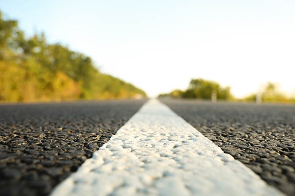 Asphalt road up close, with the horizon far away.