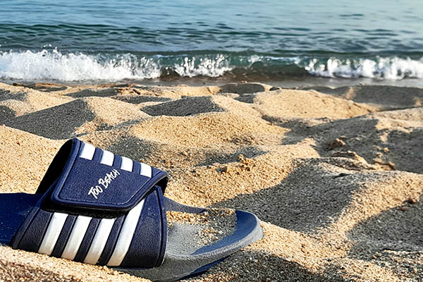 Sandal with the print to beach, on a beach. Waves rolling in.