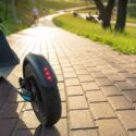 Electric kickscooter parked on a path, with sunshine reflection on the path.