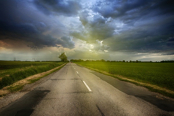 Storm above a road that leads into the distance.